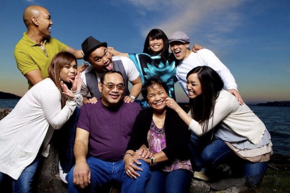 Patrick and Mary seated on a seawall at sunset, surrounded by their laughing children